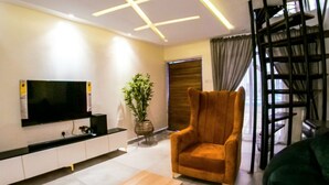 Een moderne woonkamer met een flatscreen televisie, een potplant, een bank en een trap.