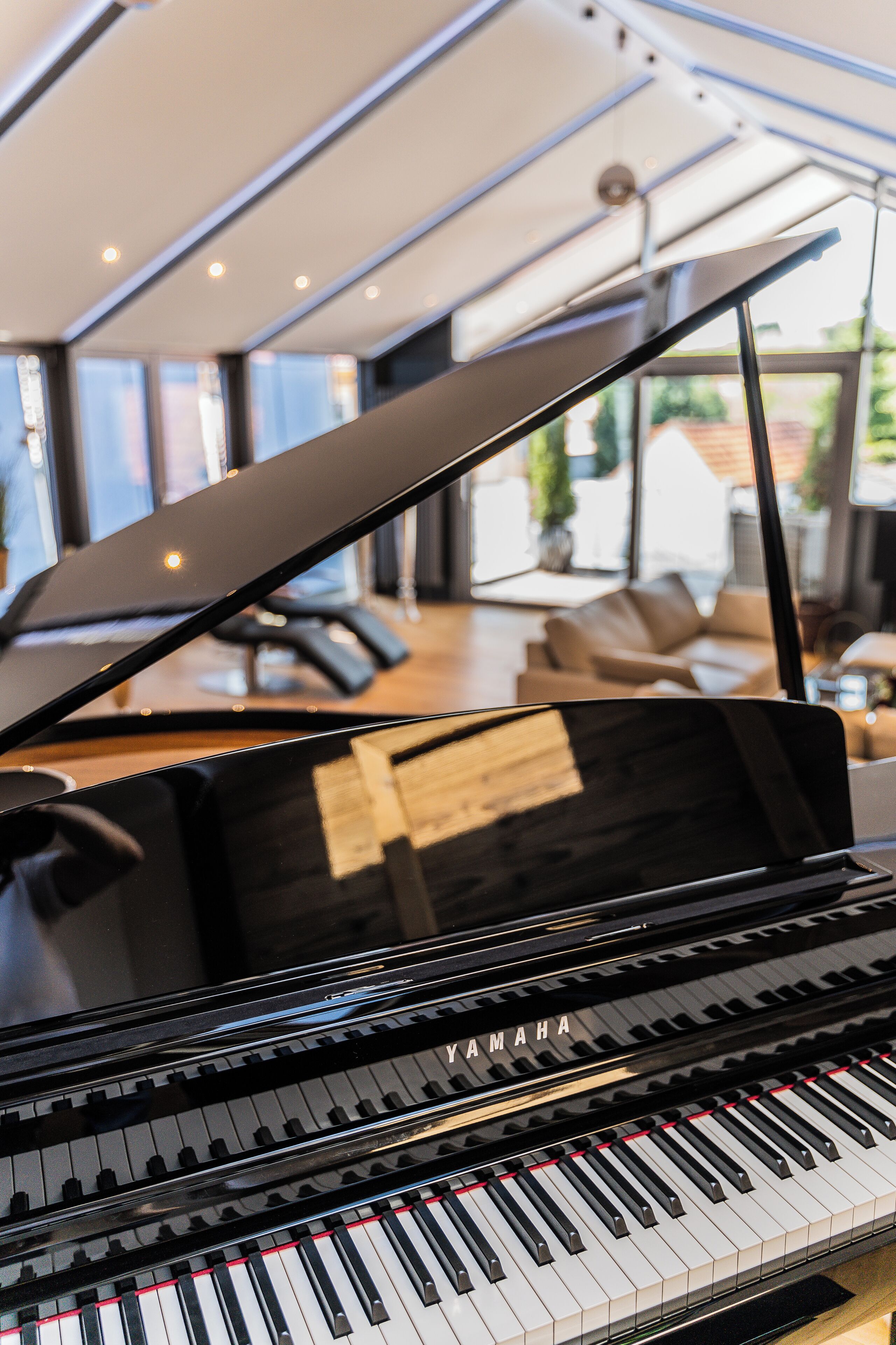 Un pianoforte a coda in una stanza luminosa con ampie finestre e vista sull'esterno.
