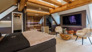 A modern bedroom with a large bed, a TV, and a fireplace. - SPA VILLA Beauty und Wellness Resort (Wingerode)