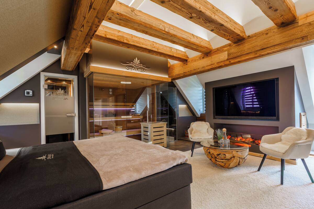 Une chambre moderne avec un grand lit, une télévision et une cheminée.