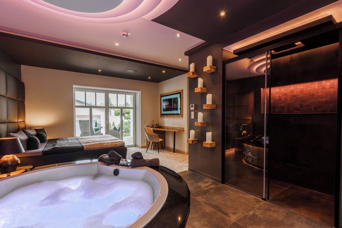 Une salle de spa moderne dotée d’une grande baignoire, d’un canapé et d’un coin repas.