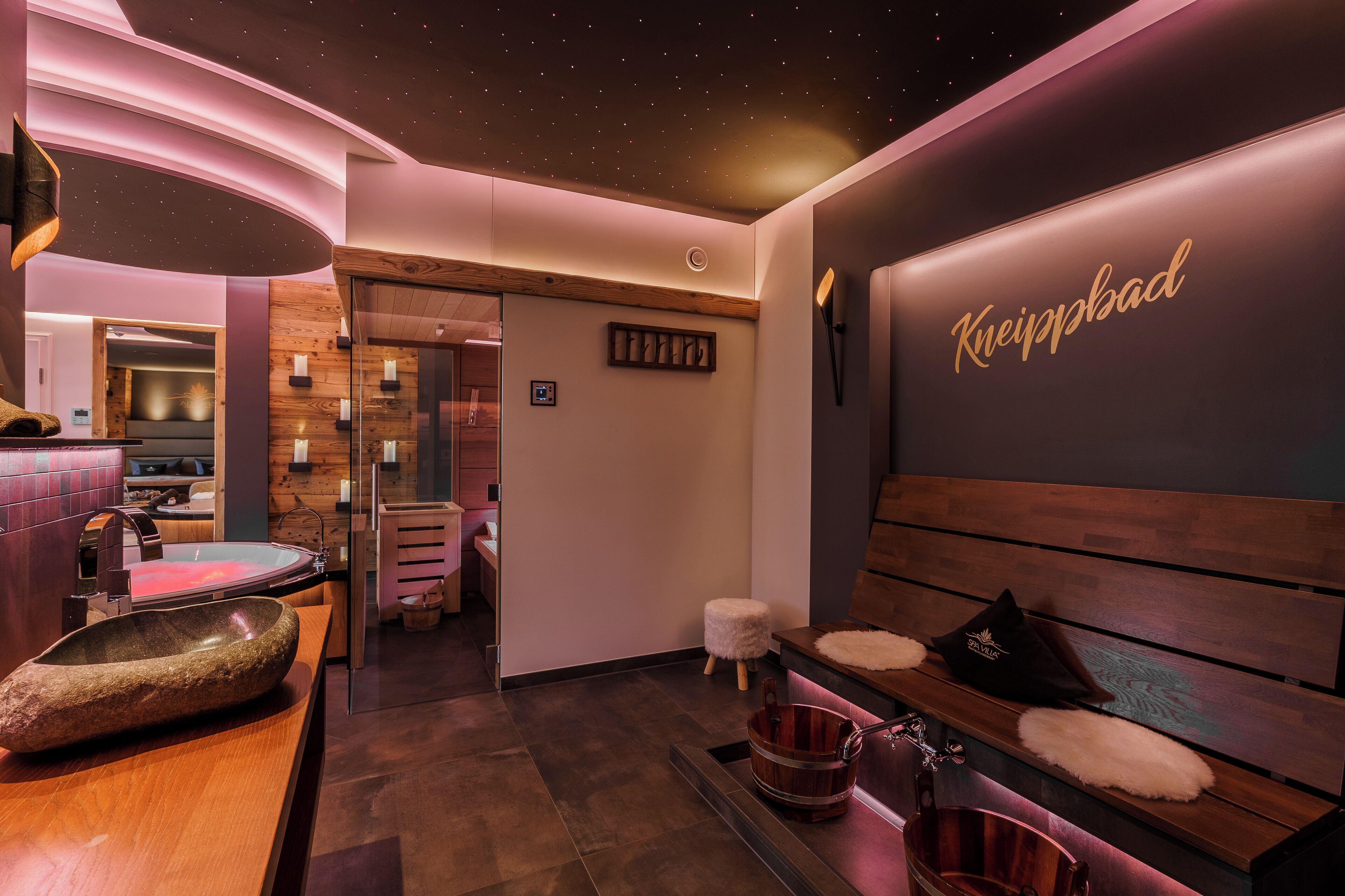 A modern spa area with a wooden bench, a stone basin, and a wall with the name 'Kneippbad'.