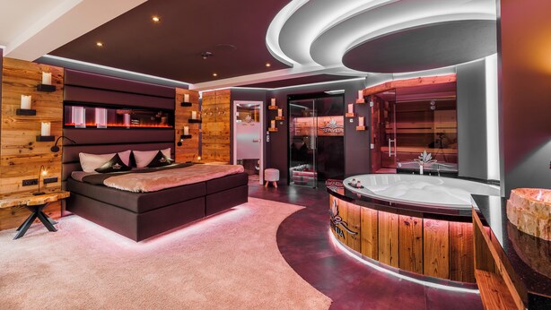 A modern spa room with a large bed, a wooden reception desk, and a hot tub. - SPA VILLA Beauty und Wellness Resort (Wingerode)