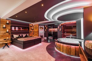 Un spa moderno con una cama grande, un mostrador de recepción de madera y una bañera de hidromasaje.