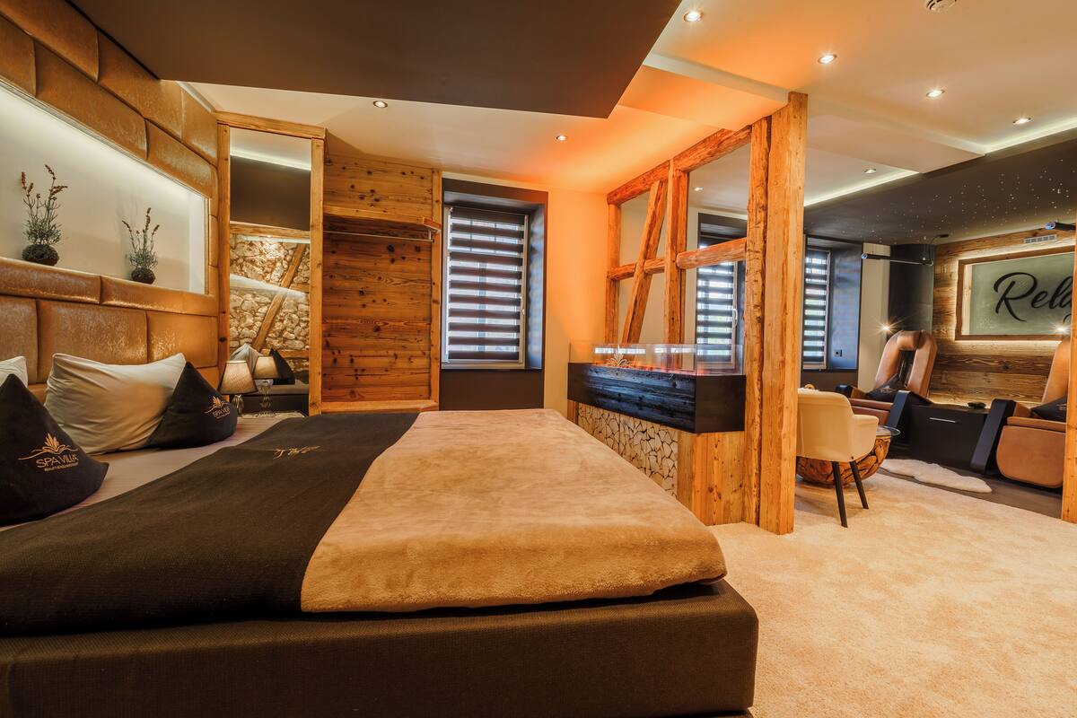 Une chambre moderne avec un grand lit, des éléments décoratifs en bois, un piano et un coin salon confortable.
