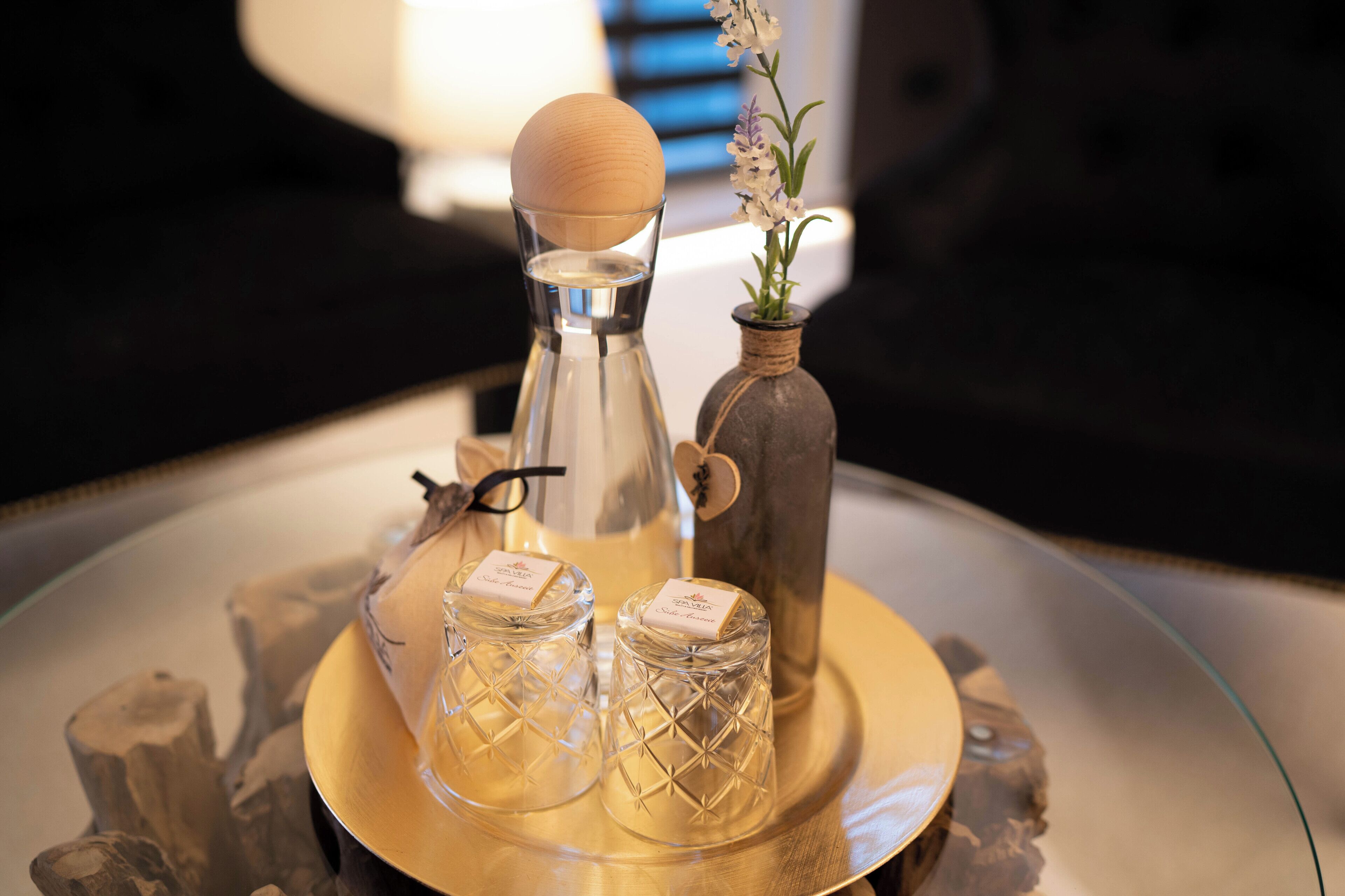 A tray with a glass decanter, two glass bottles, and a vase with flowers.