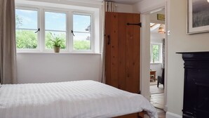A bedroom with a bed, a window with a view, a wooden door, and a fireplace.