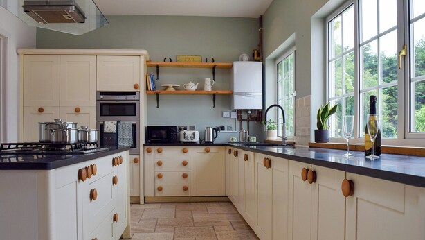 A modern kitchen with white cabinetry, a black countertop, and a window providing a view of greenery outside.