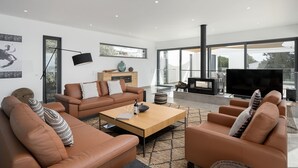 Uma sala de estar moderna com sofás de couro, uma mesa de centro de madeira e uma televisão de tela plana grande.
