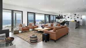 Uma sala de estar ampla com uma grande janela com vista para o mar, uma cozinha moderna e um espaço de estar aconchegante.