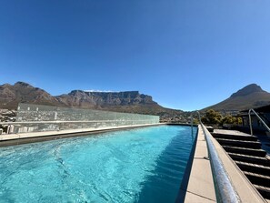 Une piscine avec une vue sur la ville et des montagnes en arrière-plan.