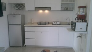 A compact kitchen with a refrigerator, stove, microwave, and sink. - E&J Residences at SOV (Cabarete)