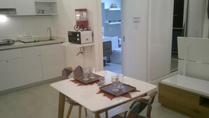 A small kitchen with a dining table set for two, a microwave, and a refrigerator. - E&J Residences at SOV (Cabarete)