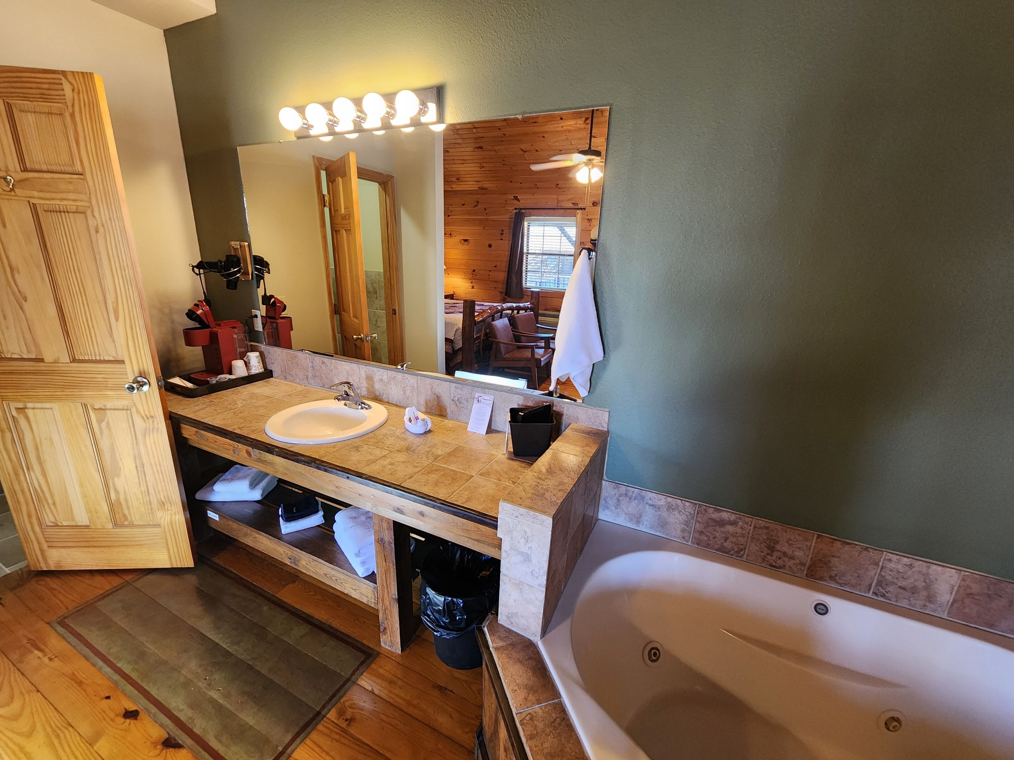 A bathroom with a wooden vanity, a sink, a mirror, a bathtub, and a shower area.