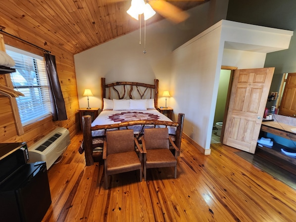 Una habitación acogedora con una cama de madera, dos lámparas de noche, un calentador y una pequeña mesa con sillas.