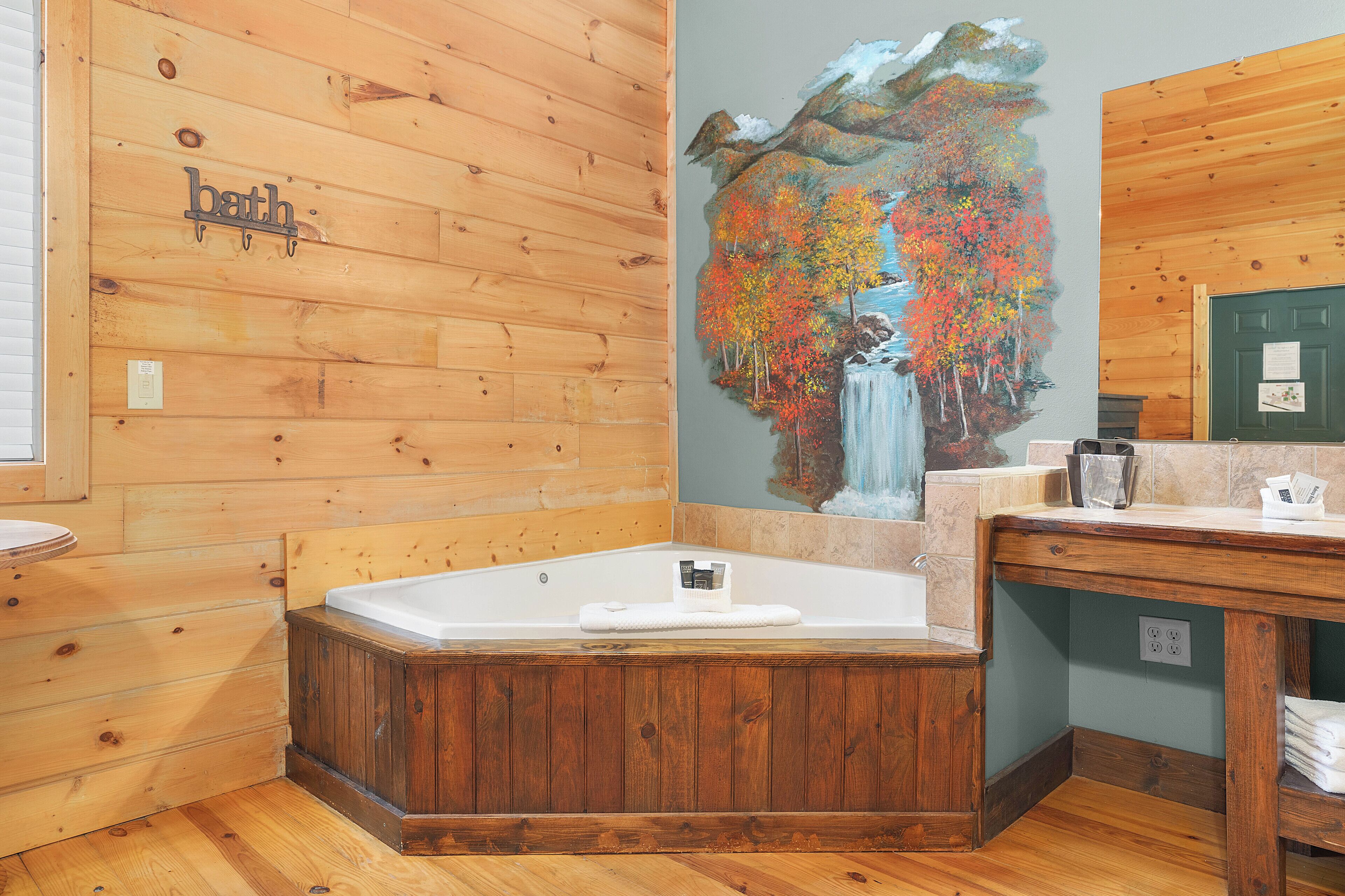 A wooden cabin bathroom with a wooden bathtub, a sink, and a mirror.