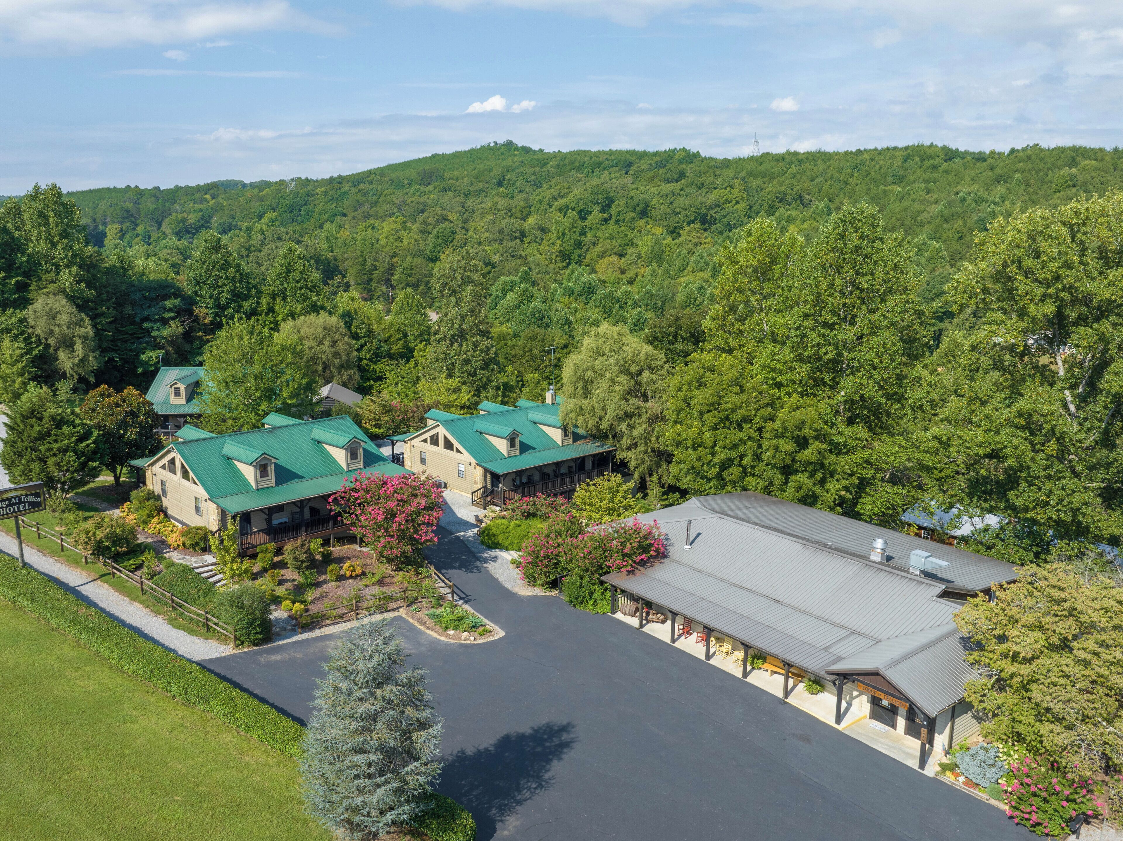 A lodge with multiple green-roofed buildings surrounded by lush greenery and hills.