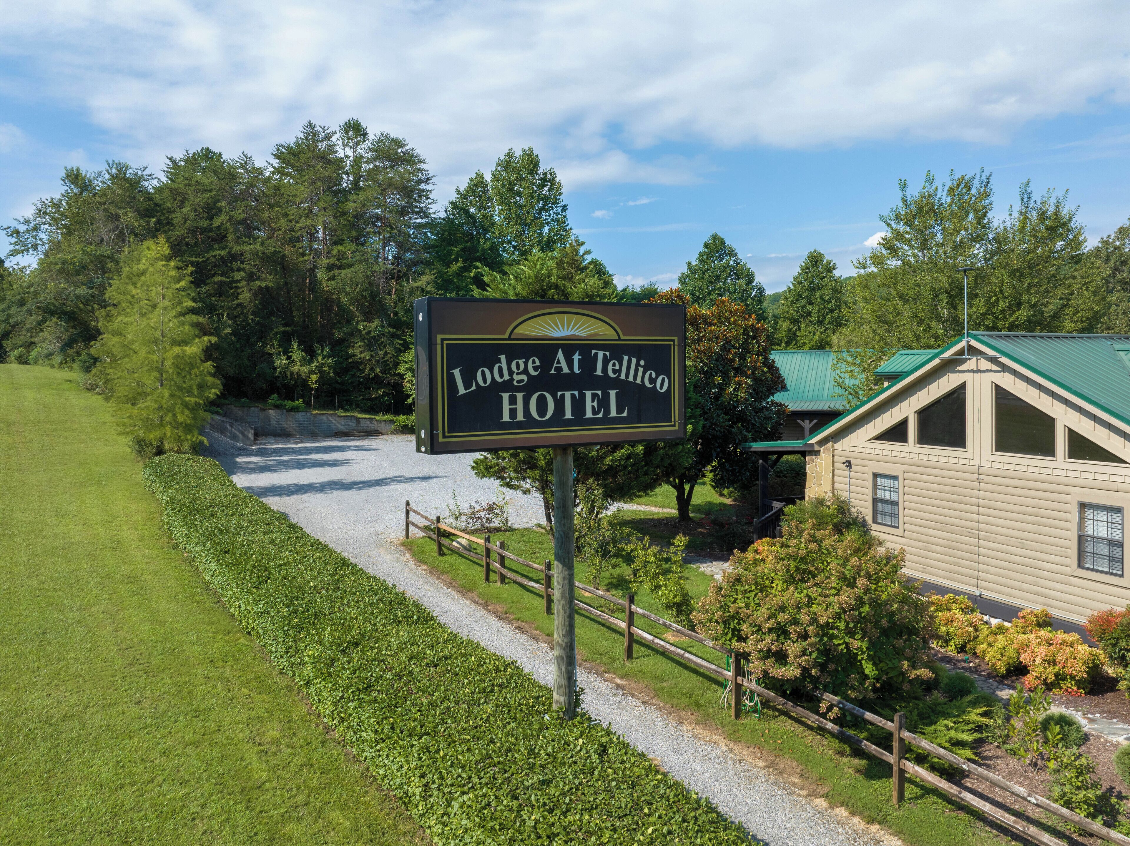 Segnaletica per Lodge At Tellico Hotel, con una strada sterrata che conduce a un edificio con tetto verde.