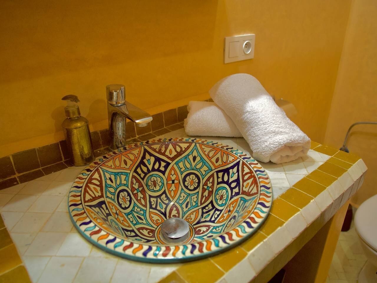 Ein Badezimmer mit einem dekorativen Waschbecken, einem Handtuch und einer Toilette.