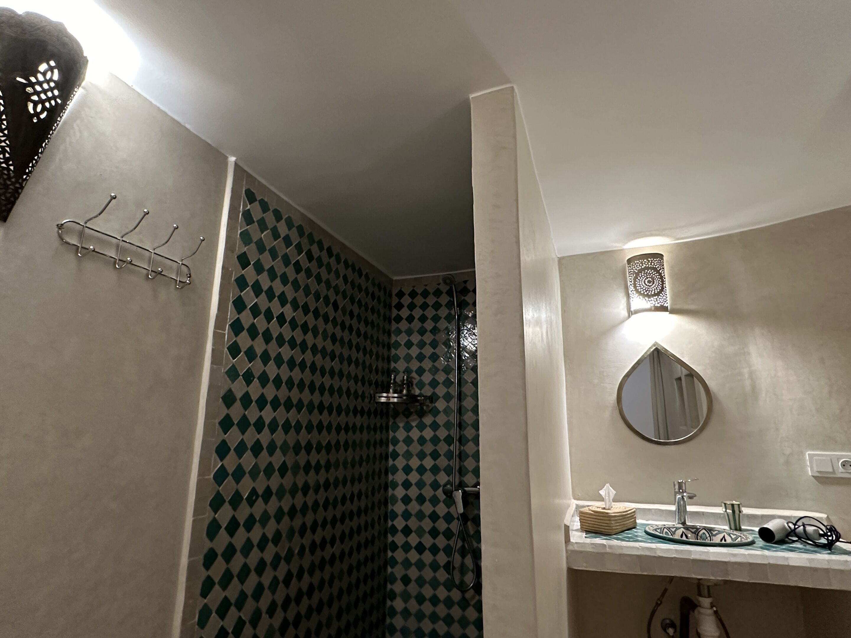 Un baño con ducha, lavabo con espejo y un perchero para toallas.