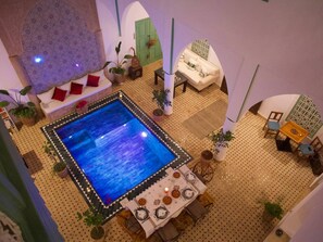 A model of a room with a pool, a sofa, a table with chairs, and various plants. - Riad Ocallaghan (Marrakech)
