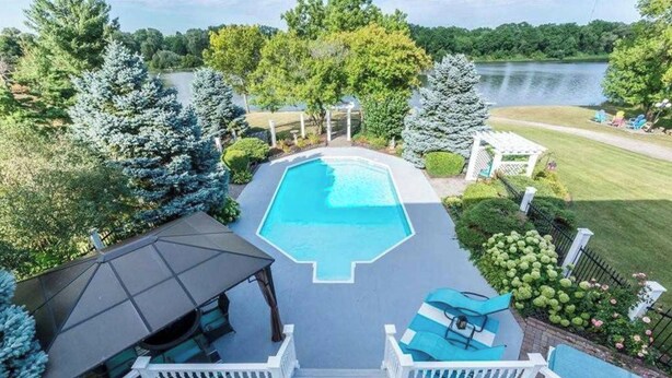 Un jardin avec une piscine, un patio couvert et une vue sur un lac.