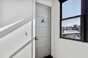 Stylish rooms feature a door with a unique design and a large window offering views of the urban landscape.