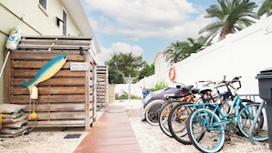 Un camí de fusta que condueix a una zona tancada amb un cartell que indica 'Smoke-Free Property', bicicletes aparcades i una palmera al fons.