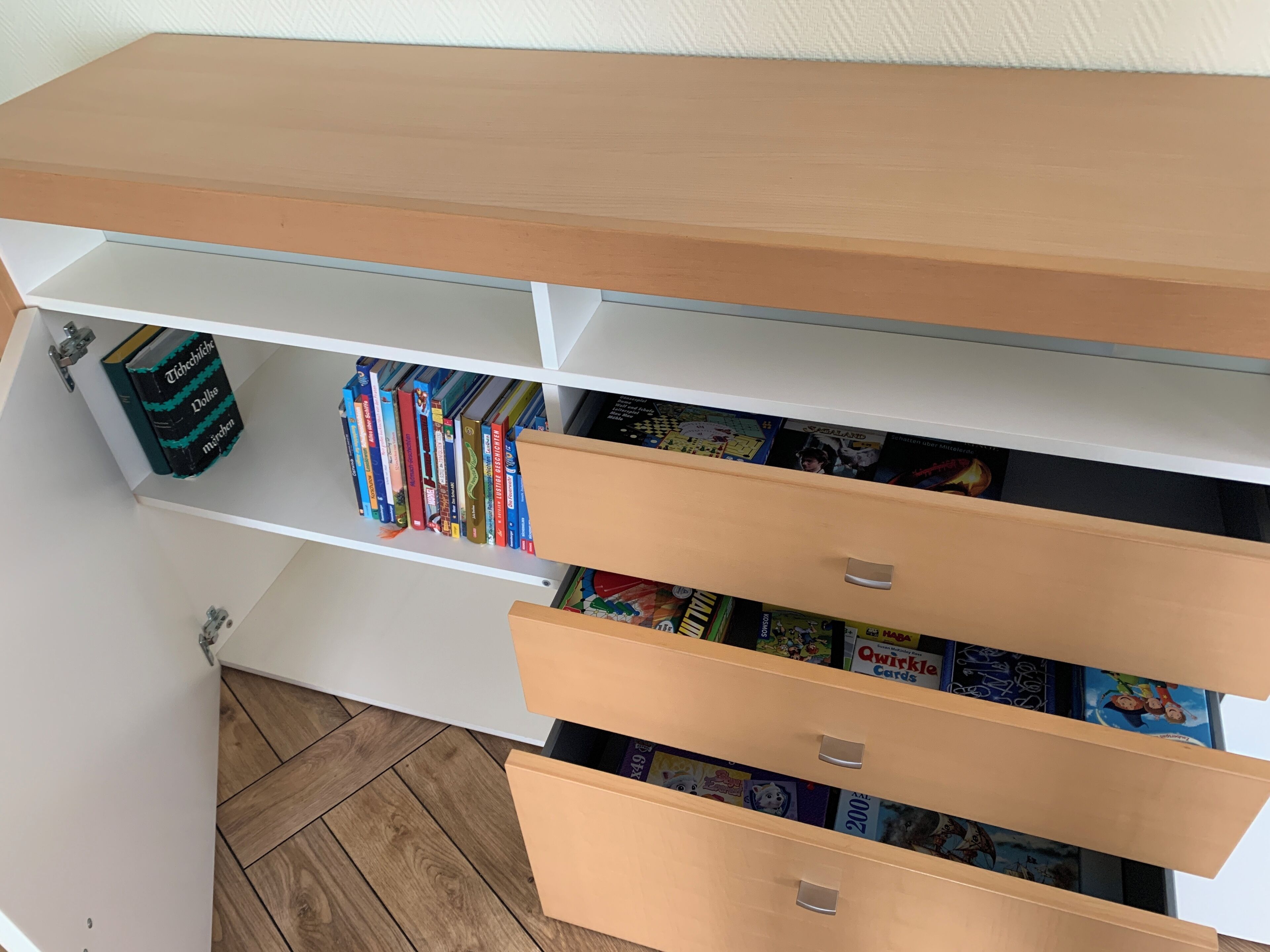 A bookshelf with books and a drawer containing cards.
