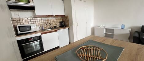A compact kitchen with a microwave, oven, sink, and a small cabinet.