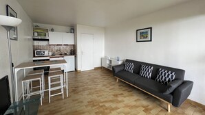 Ein kompakter Wohnbereich mit einer Küchenzeile, einem Essbereich und einer Couch.