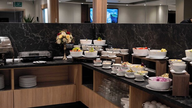 A buffet setup with various dishes and bowls on a marble counter. - Les Deux B Salsabil (Algiers)