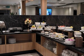 Un buffet con diversos platos y recipientes sobre una encimera de mármol.