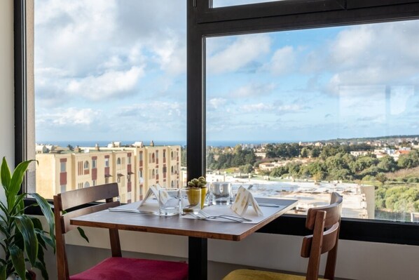 A dining table set with a view of a cityscape through a large window. - Les Deux B Salsabil (Algiers)