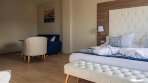 A hotel room with a large bed, a seating area, and a painting on the wall. - Les Deux B Salsabil (Algiers)