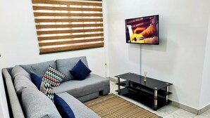 Ein modernes Wohnzimmer mit einem grauen Ecksofa, einer schwarzen TV-Konsole und einem Teppich.