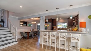 Eine moderne Küche mit Barbereich, Holzboden und einem Essbereich mit Stühlen und Tisch.