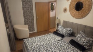 A bedroom with a bed, a chair, a door, and decorative wall art. - Beas Ferienglück (Busenberg)