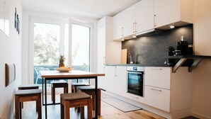 Una cucina moderna con mobili bianchi, un tavolo da pranzo in legno e un'ampia finestra.