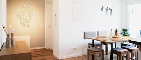 A modern dining area with a wooden table, chairs, and a wall-mounted light fixture.