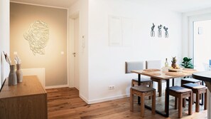 Ein zeitgemäßer Essbereich mit Holztisch, Stühlen und einer Wandleuchte.