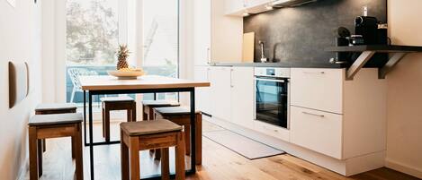 Una cocina compacta con armarios blancos, horno integrado y cafetera.