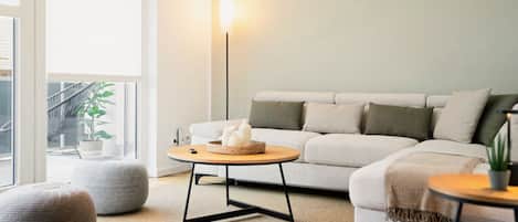 Un salon moderne avec un canapé, une table basse ronde, un lampadaire et une plante en pot.