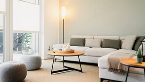 Ein modernes Wohnzimmer mit einer Couch, einem runden Couchtisch, einer Stehlampe und einem Blumentopf.