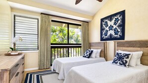 A hotel room with two beds, a wooden dresser, a window with curtains, and a ceiling fan.