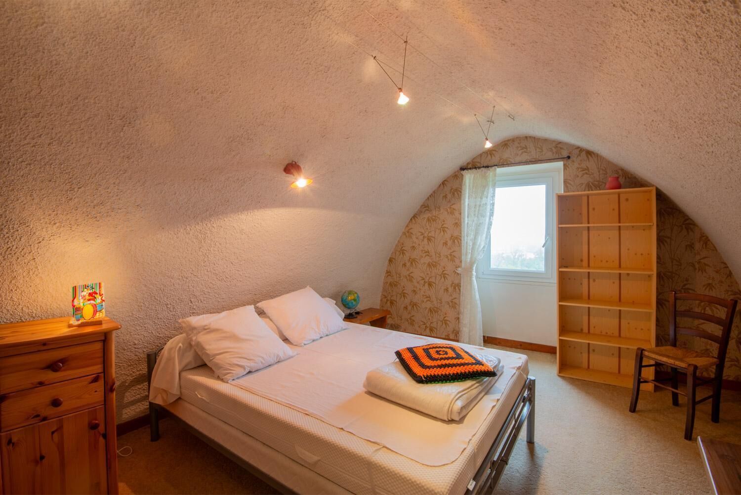 Une chambre avec un lit superposé, une commode en bois, une bibliothèque et un globe terrestre posé sur une table de chevet.
