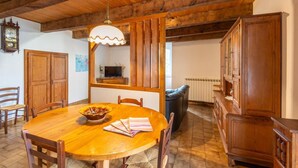 Ein Esszimmer mit Holzboden, einem großen Tisch, Stühlen und einer Kandelaber.