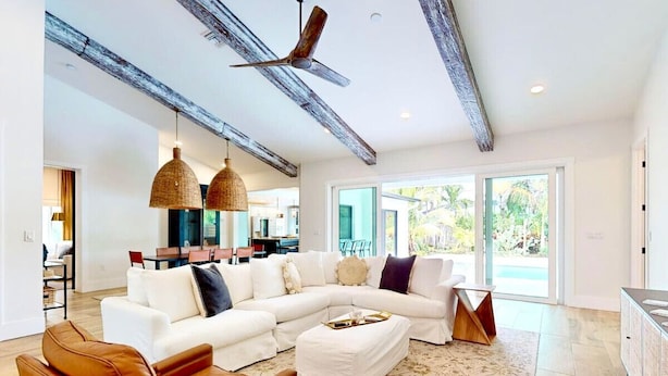 A modern living room with a sectional sofa, a wooden coffee table, and a ceiling fan. - HARDING HAVEN Spacious pool home 1 block to the beach, walk to Cocoa Beach Pier! (Cocoa Beach)
