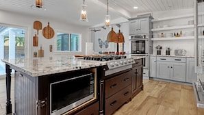 A modern kitchen with a large island, stainless steel appliances, and pendant lighting. - HARDING HAVEN Spacious pool home 1 block to the beach, walk to Cocoa Beach Pier! (Cocoa Beach)