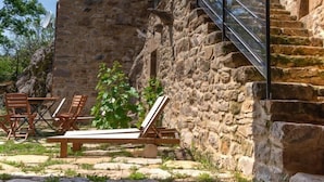 Un bâtiment en pierre avec un escalier menant à un balcon agrémenté de plantes en pot.
